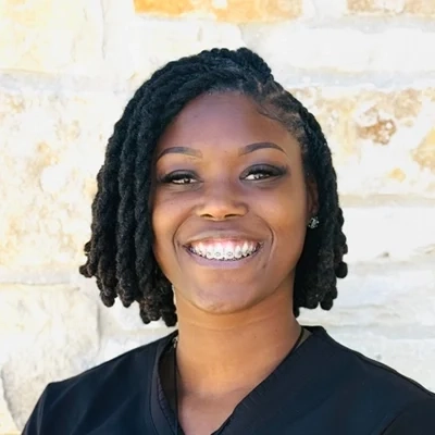 Dr. Shaquita Kelly smiling in front of a stone wall.
